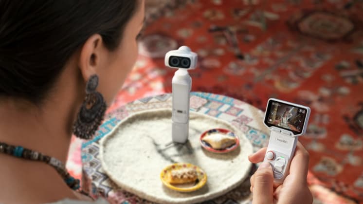 Traveler framing a shot on the Insta360 Luna Ultra detachable touchscreen while the camera stands on a table