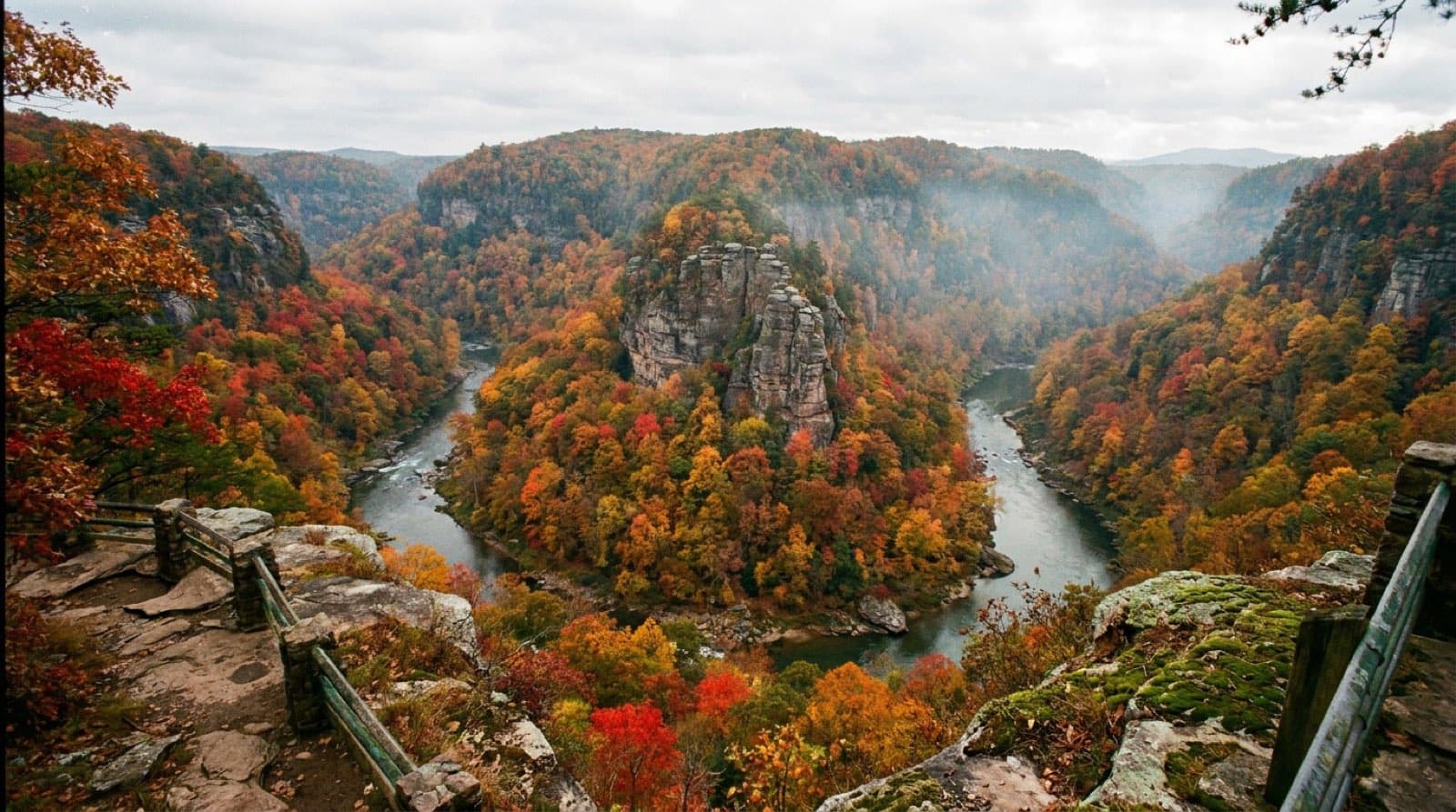 The Grand Canyon of the South at Breaks Interstate Park, a deep forested gorge with the Russell Fork river bending around the towering rock formation called The Towers, blazing autumn color filling the canyon, dramatic depth