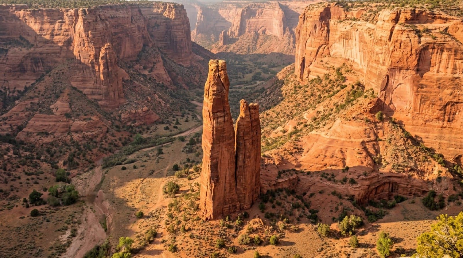 The 800-foot Spider Rock sandstone spire rising from the floor of Canyon de Chelly with sheer red rock walls in warm late light