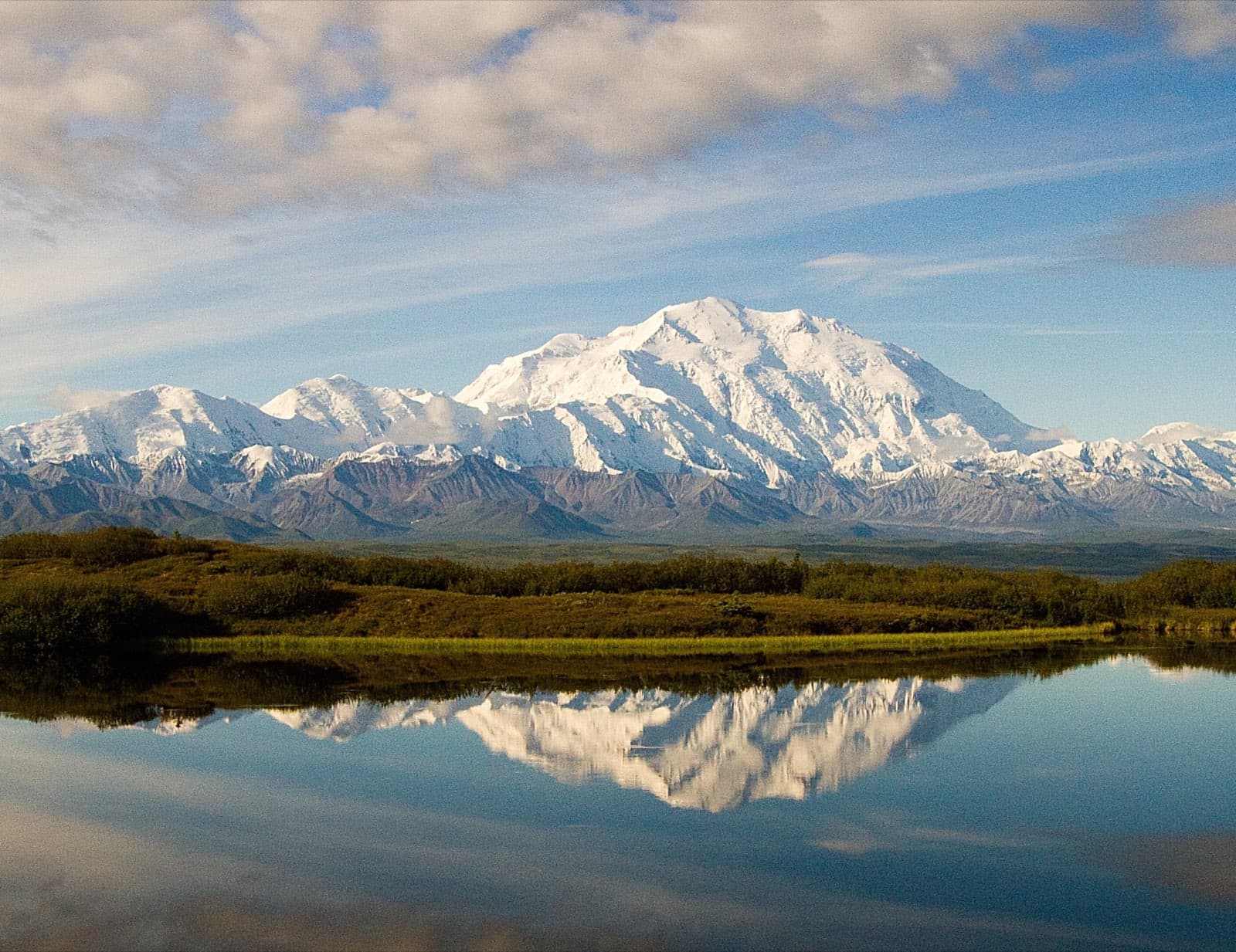The snow-capped peak of Denali (Mount McKinley), North America's tallest mountain, mirrored in the calm waters of Wonder Lake under a clear sky in Denali National Park and Preserve, Alaska.
