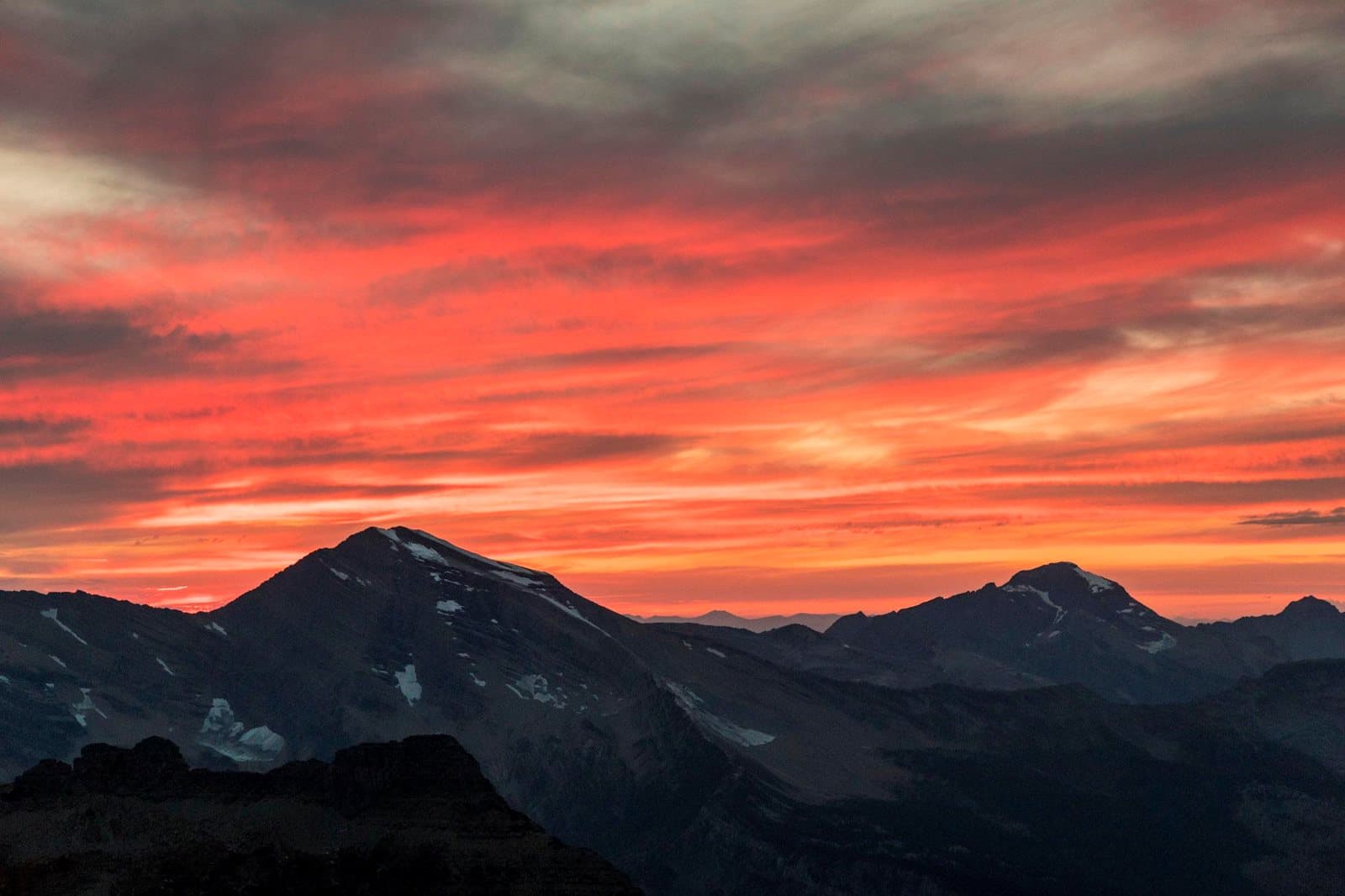 Orange sunset clouds over Glacier National Park peaks