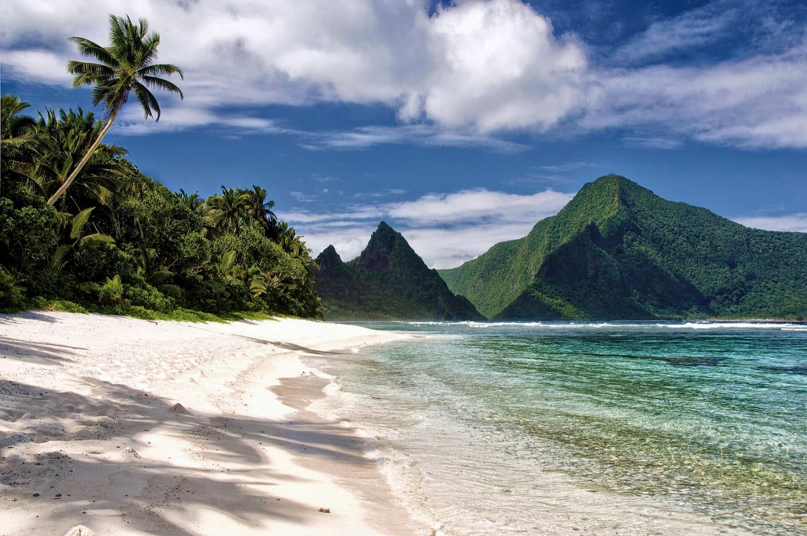 Ofu Beach with white sand, reef water, and green volcanic slopes
