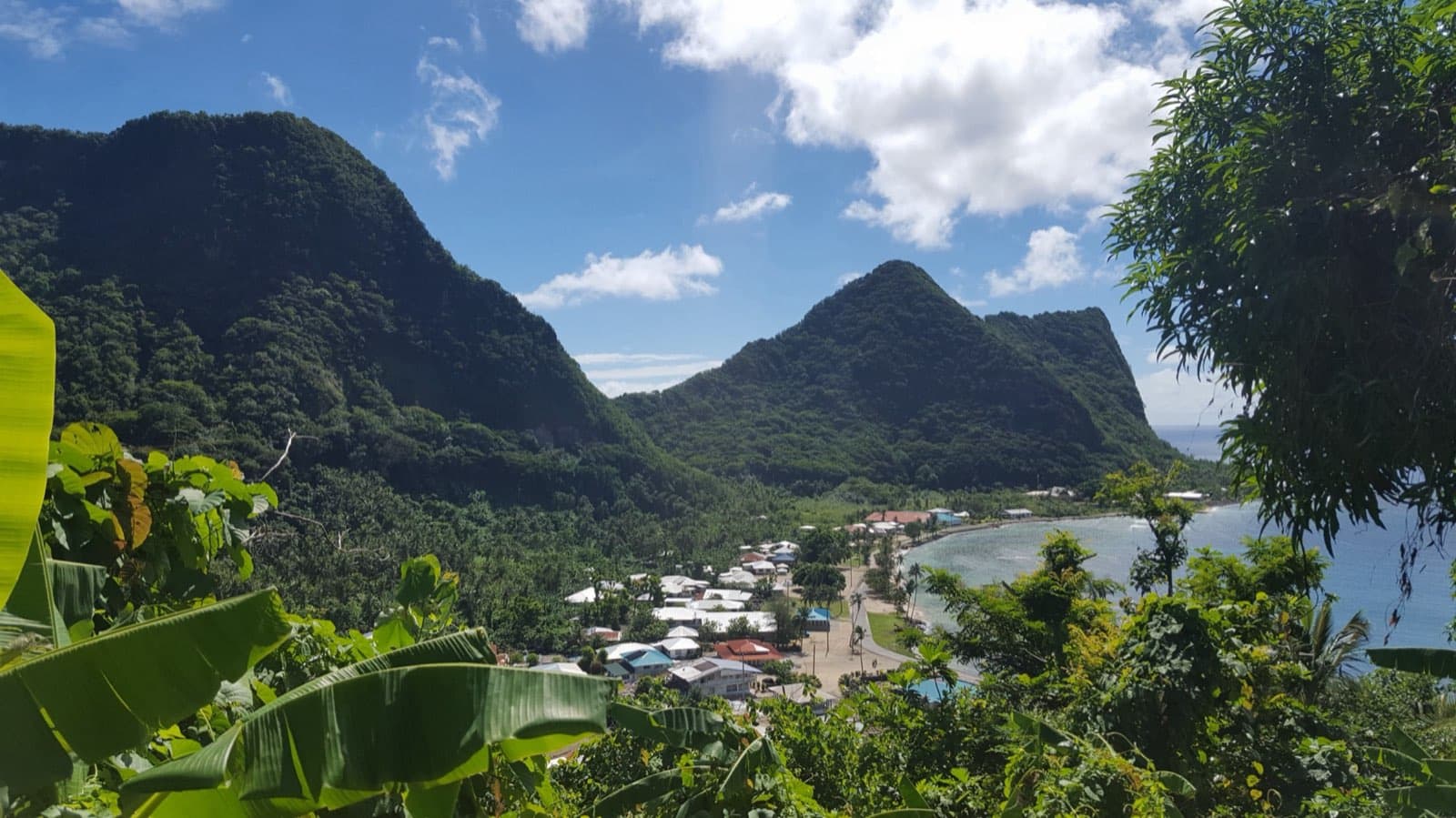 View of Vatia village and its bay framed by steep rainforest-covered ridges and Pacific Ocean coastline, seen from the Tuafanua Trail in the National Park of American Samoa on Tutuila Island.