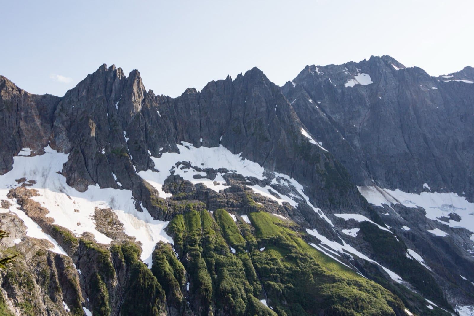Jagged glacier-capped peaks of The Triplets, Cascade Peak, and Johannesburg Mountain rising above forested ridges along the Cascade Pass Trail in North Cascades National Park, Washington.