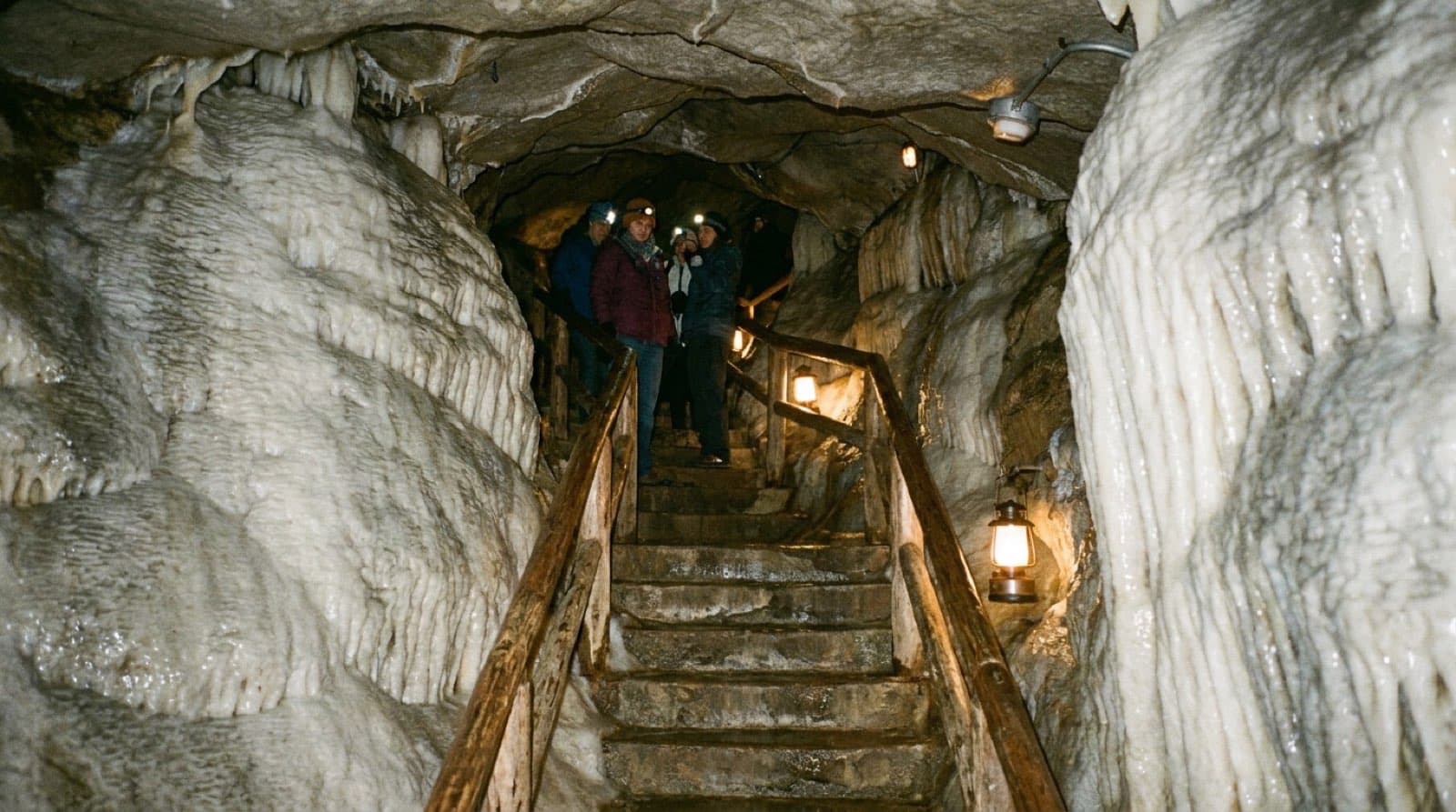 Marble cave passage at Oregon Caves National Monument, flowstone and rippled white-and-grey marble walls, stone stairs winding through, soft guided-tour lighting