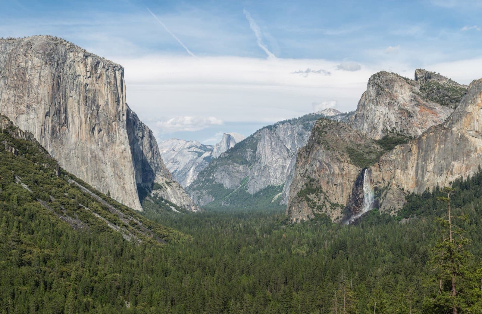Yosemite Valley seen from Tunnel View, with El Capitan rising on the left, Bridalveil Fall on the right, and Half Dome in the distance under a clear sky