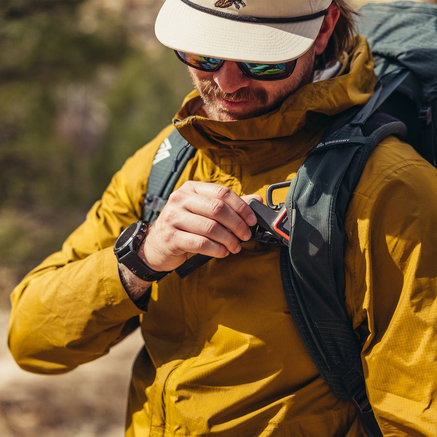 Hiker in a yellow jacket buckling the sternum strap of a Gregory Paragon 60