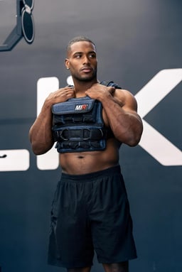 A person wearing the miR Air Flow weighted vest, front view in a gym