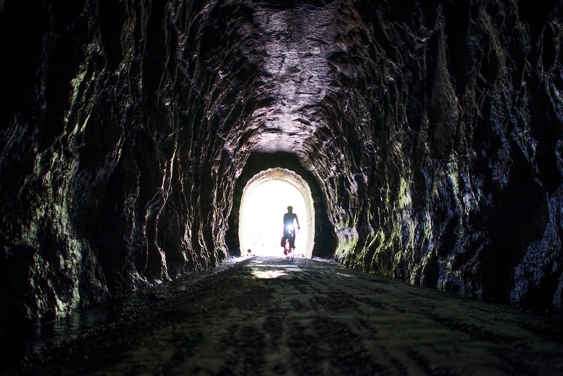 A cyclist approaching daylight inside an Elroy-Sparta State Trail tunnel