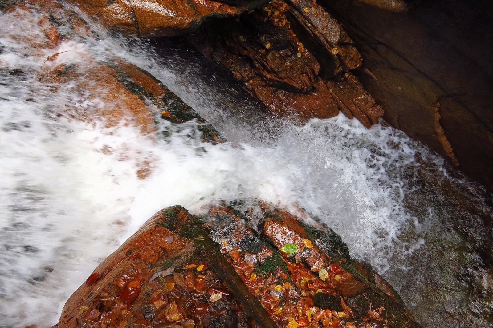 Flume Brook churning white over red granite ledges inside the gorge