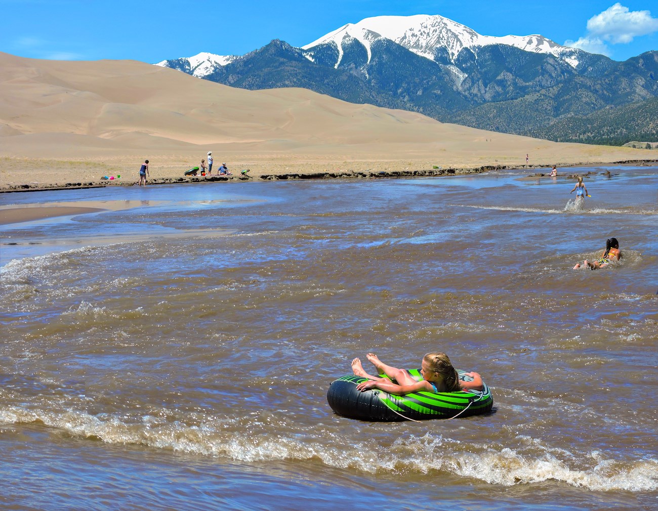 A child tubing in seasonal Medano Creek below the dunes