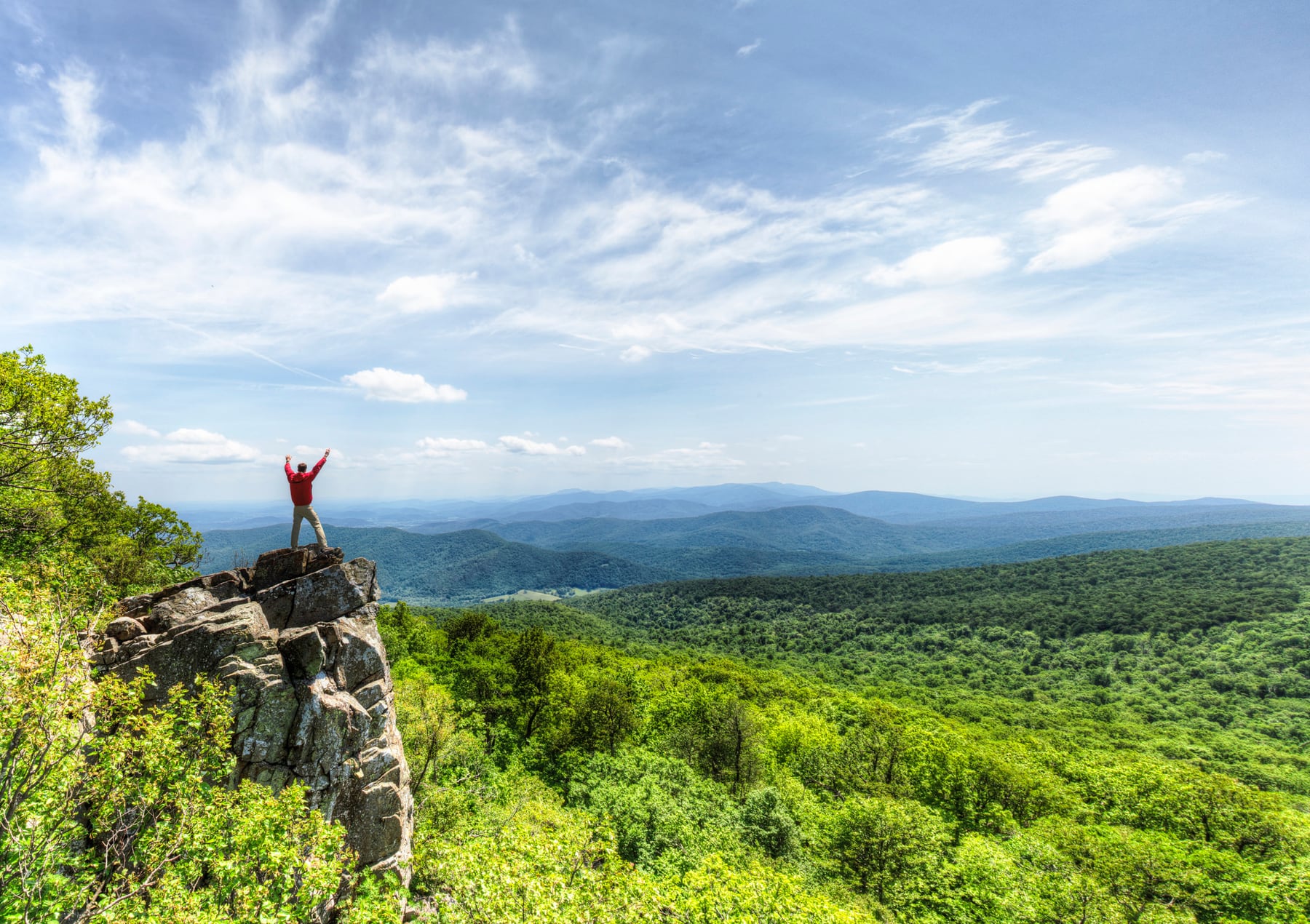 A hiker standing on a rocky Blue Ridge overlook in Shenandoah
