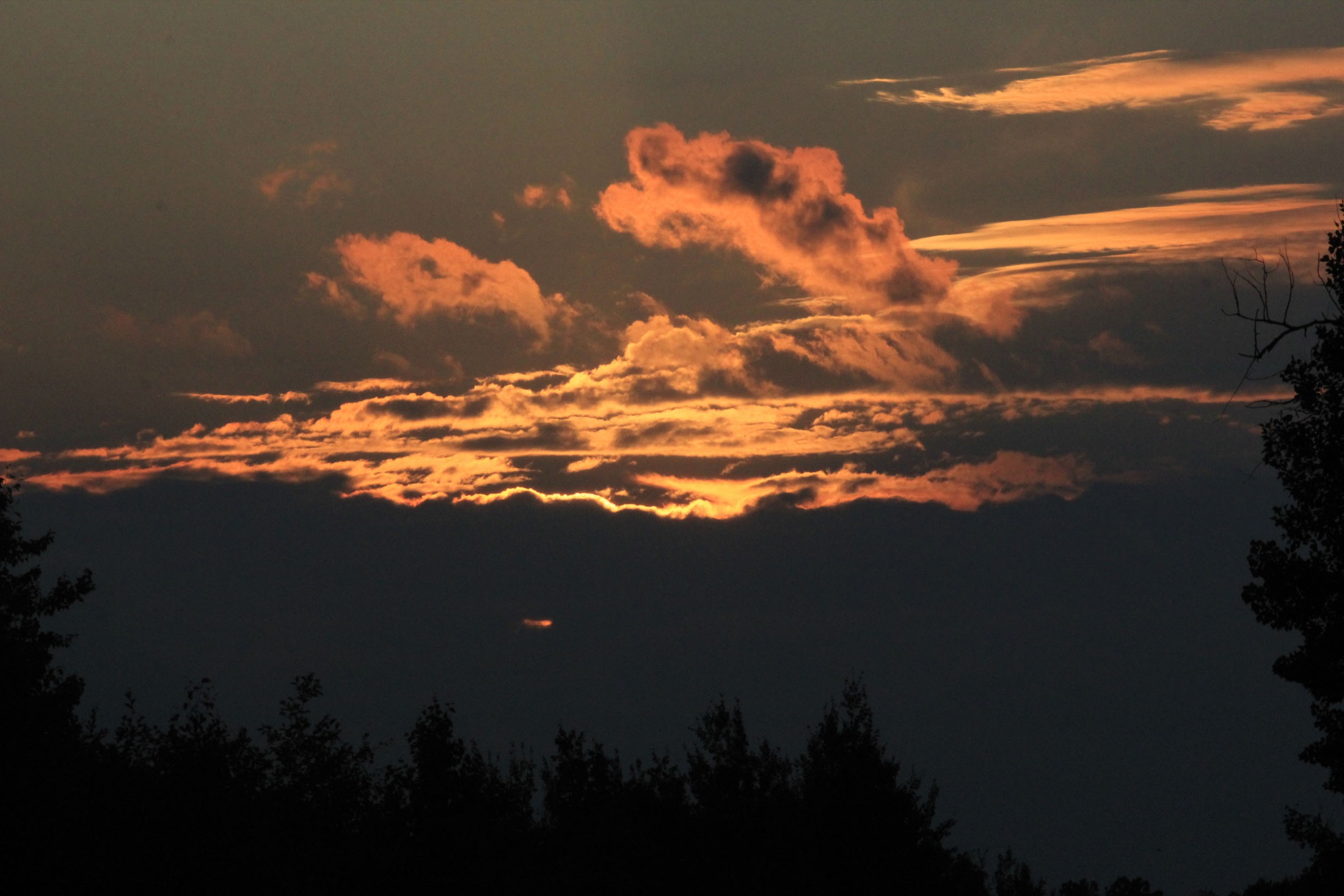 Dusk over Voyageurs National Park in northern Minnesota, with dramatic clouds glowing at sunset above the calm lake water and dark treelined shoreline