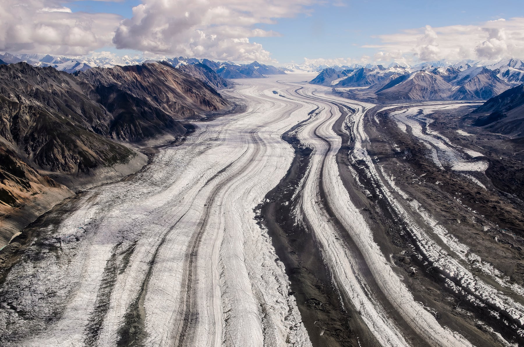 Logan Glacier striped with rock between barren mountain slopes