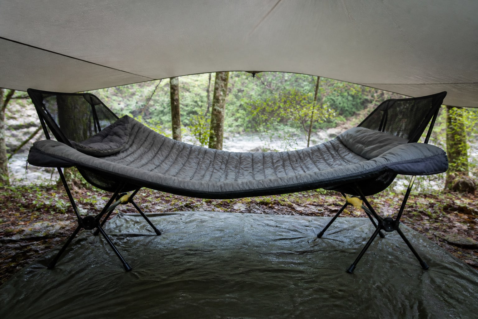 A damp sleeping bag opened and draped under a ventilated tarp to air dry