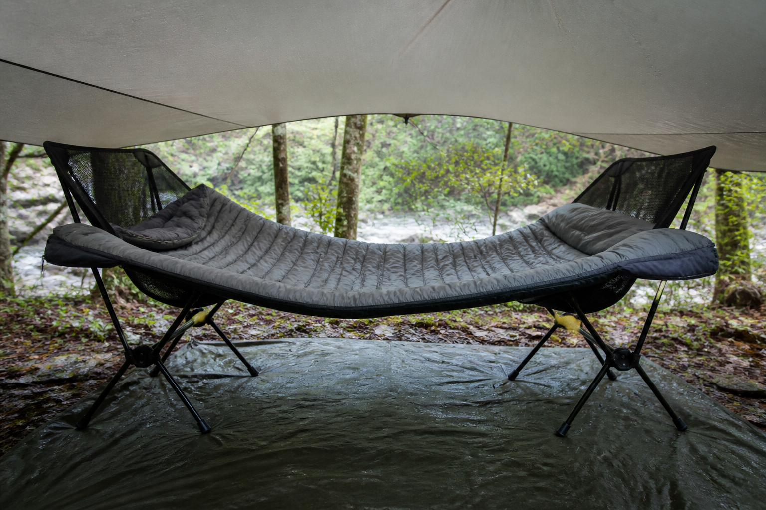 A damp sleeping bag opened and draped under a ventilated tarp to air dry
